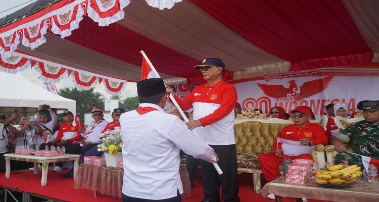 Bupati Bone Bolango, Drs. H. Ismet Mile, MM, saat menerima bendera Merah Putih dalam Apel Gerakan Pembagian Benderah Merah Putih Tahun 2025 tingkat Kabupaten Bone Bolango yang digelar di Danau Perintis Desa Boludawa, Jum'at 1 Agustus 2025. 